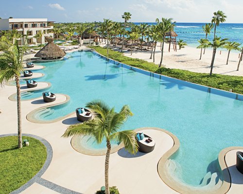 An outdoor swimming pool alongside the sea and resort units.