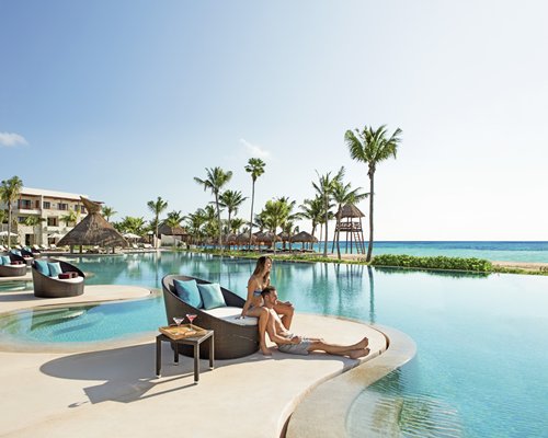 An outdoor swimming pool alongside the sea and resort units.