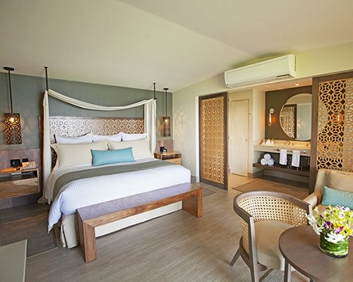 A well furnished bedroom with a king bed and open sink vanity.
