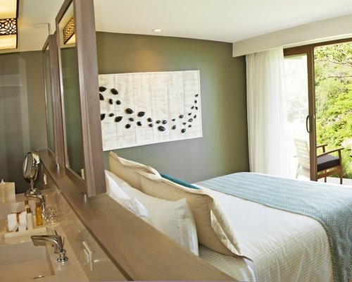 A well furnished bedroom with king bed sink and balcony.
