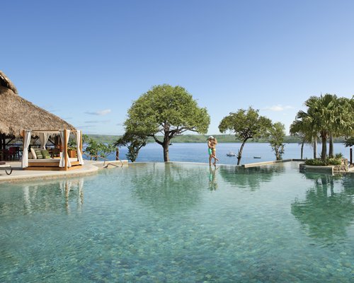 A large outdoor swimming pool with cabana alongside the waterfront.