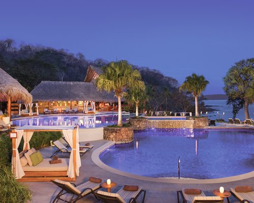 An outdoor swimming pool with chaise lounge chairs and beach bed alongside the resort.