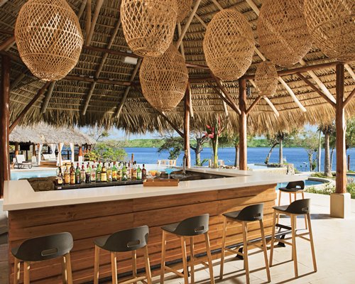 Outdoor swimming pool with a thatched covered poolside bar.