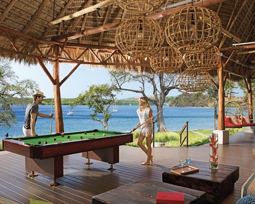 An indoor recreational room with pool table alongside the ocean.