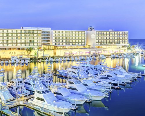Exterior view of Breathless Cabo San Lucas Resort & Spa alongside the ocean with boats at a marina.