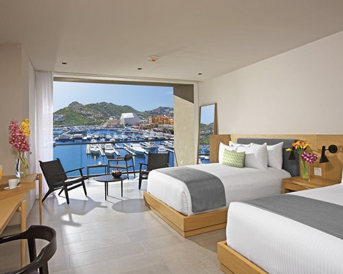 A well furnished bedroom with two beds and a balcony.