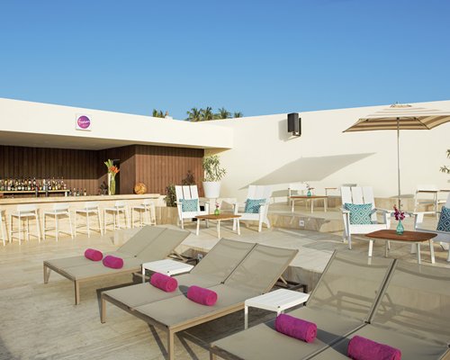View of chaise lounge chairs and patio furniture alongside an outdoor bar.