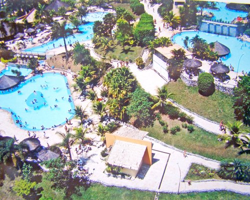 An aerial view of outdoor swimming pool with thatched sunshades and swim up pool bars.