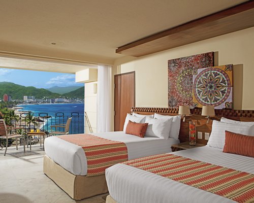 A well furnished bedroom with two beds and a balcony.