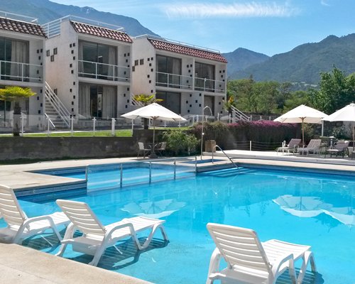 Outdoor swimming pool with lounge chairs in a shallow water sunning area.