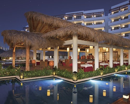 A fine dining restaurant alongside the waterfront and resort units at night.