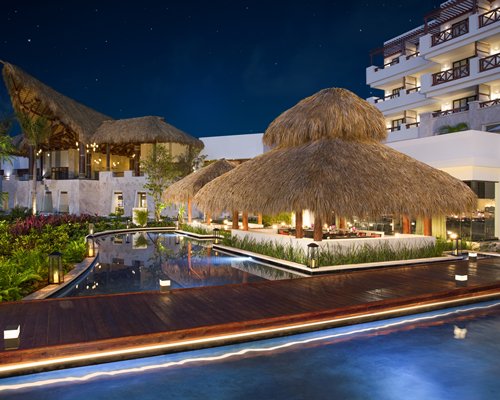 An outdoor swimming pool alongside the resort unit at night.
