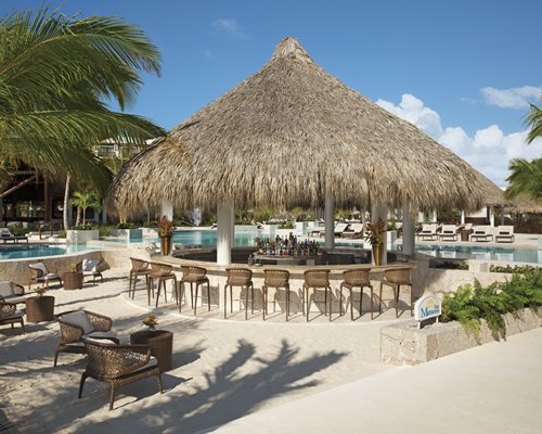 A poolside bar with chaise lounge chairs and trees.