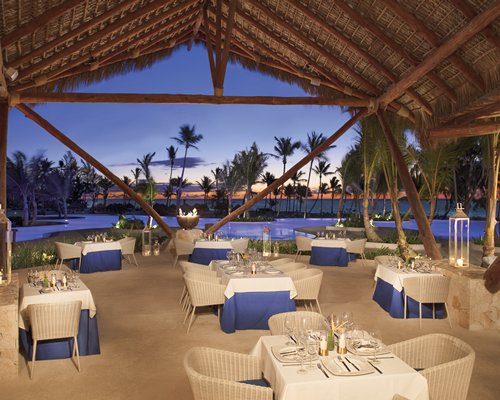 An outdoor fine dining area at the resort with thatched roofs.