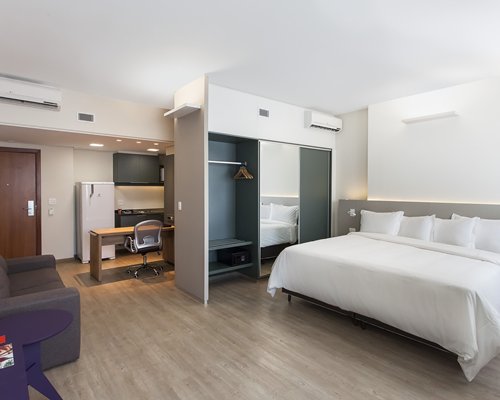 A well furnished bedroom with a queen bed and open plan kitchen.