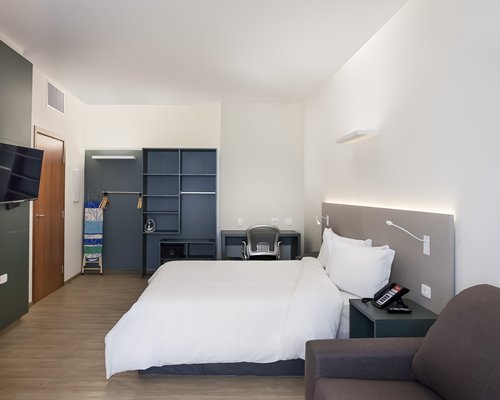 A well furnished bedroom with a queen bed and a television.