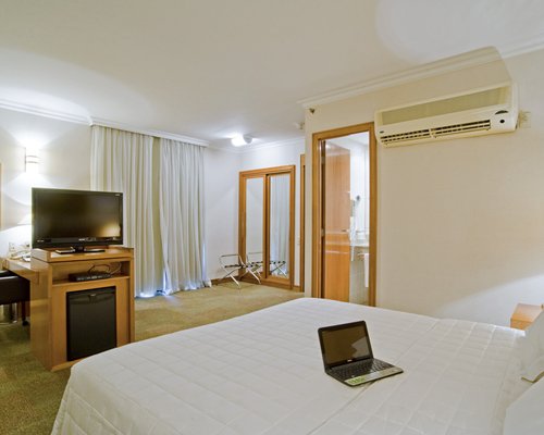 A well furnished bedroom with a television and laptop.