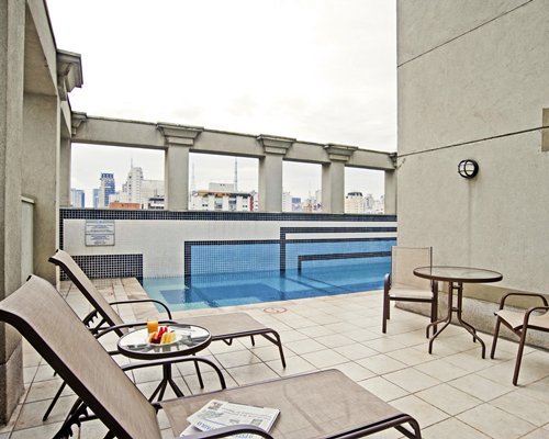 Outdoor swimming pool with chaise lounge chairs and patio chairs.