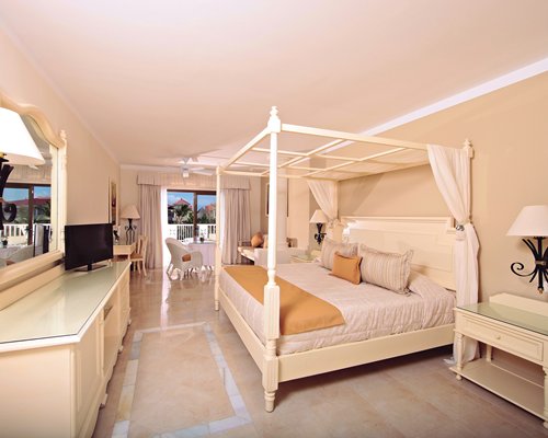 A well furnished bedroom with a television sofas and an outside view.