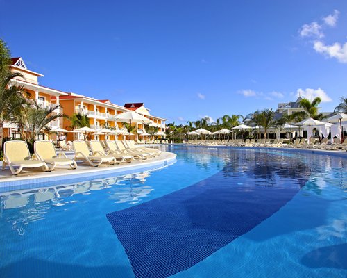 An outdoor swimming pool with chaise lounge chairs and sunshades alongside the resort unit.