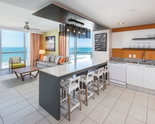A WELL FURNISHED LIVING ROOM WITH AN OPEN PLAN KITCHEN AND BREAKFAST BAR.