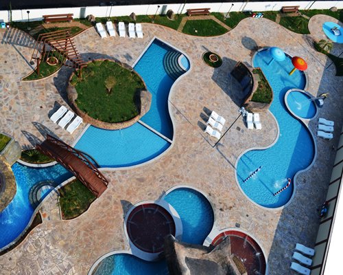 An aerial view of an outdoor swimming pool with chaise lounge chairs alongside the resort.