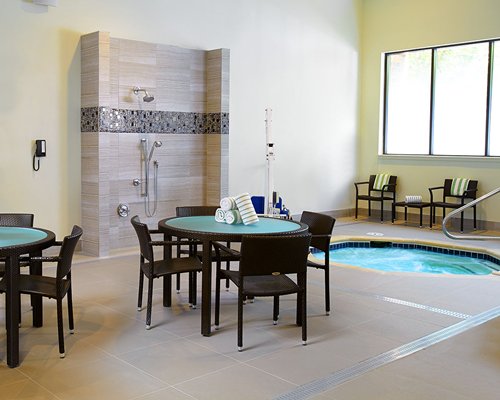 An indoor hot tub with shower and patio furniture.