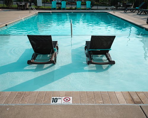 Scenic exterior view of the outdoor swimming pool with chaise lounge chairs and patio chairs.