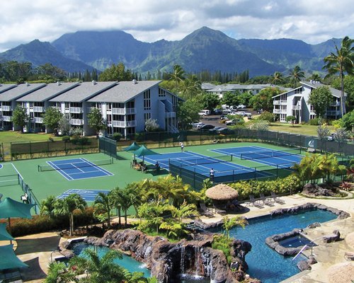 Scenic aerial view of resort overlooking pools with tennis courts and mountain views.