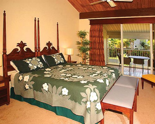 A furnished bedroom with a large bed and sliding doors onto balcony with seating.