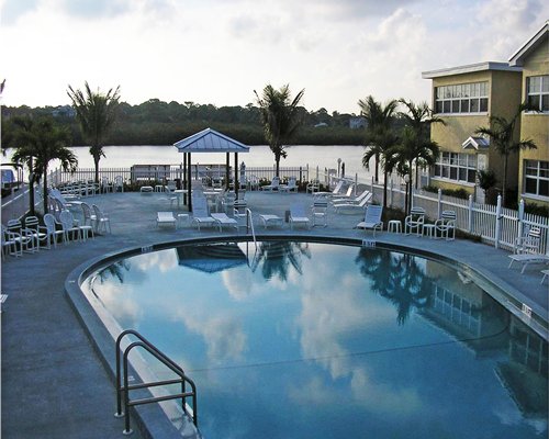 An outdoor swimming pool with chaise lounge chairs alongside a multi story resort unit.