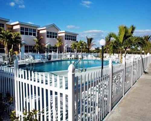 An outdoor swimming pool with chaise lounge chairs alongside a barefoot Beach Resort.