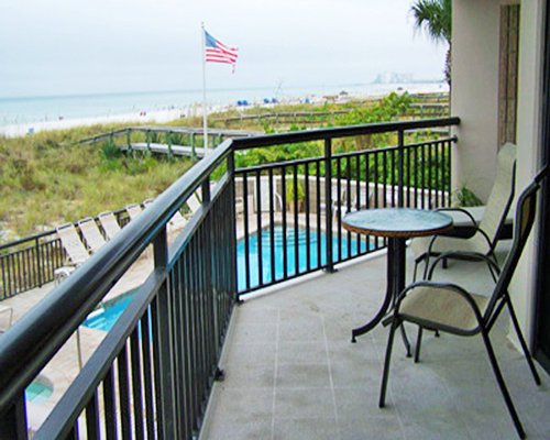 A balcony with a patio furniture alongside an outdoor swimming pool.