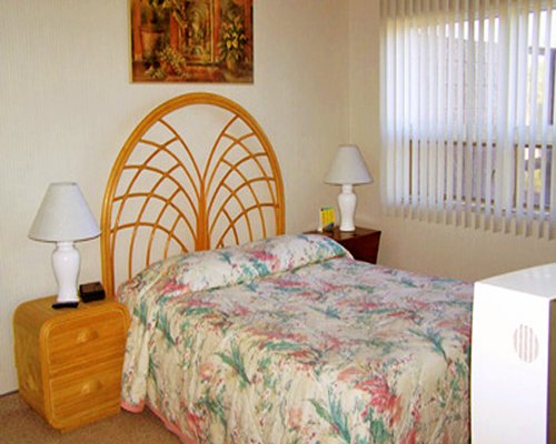A well furnished bedroom with two lamps and an outside view.