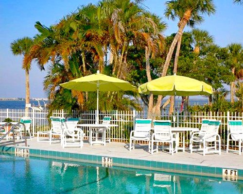 An outdoor swimming pool with chaise lounge chairs and sunshades.