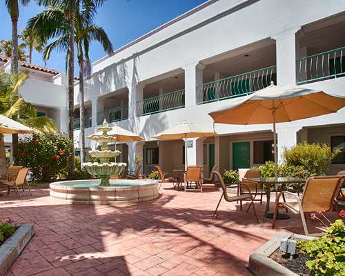 A view of resort courtyard area with fountain and umbrella table seating.