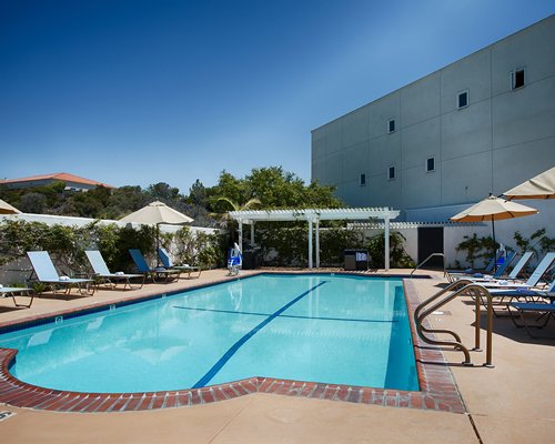 A resort pool and patio area with chaise lounges and umbrella seating.