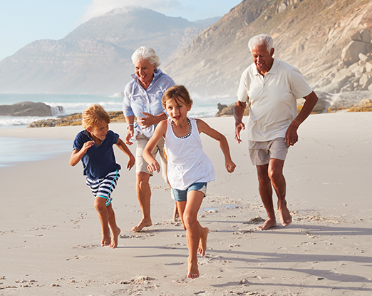 Grandparents and grandchildren running on a beach