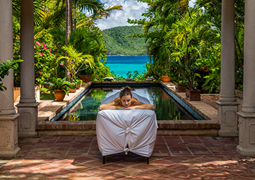 A woman laying on a massage table at a tropical spa