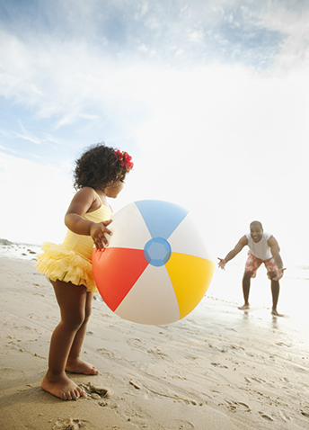 A father and daughter playing catch with a beach ball