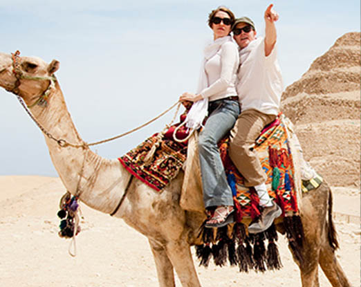 A couple riding on a camel in the desert in the Pyramids at Giza