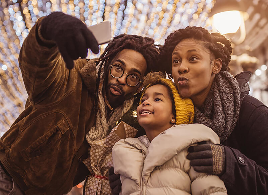 A Black family smiling and taking a picture in winter wear