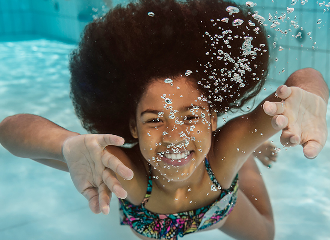 A smiling girl underwater in a pool