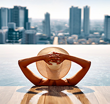 A woman in a sun hat relaxing in a pool overlooking a city