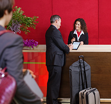 A man checking into a hotel with a woman attending