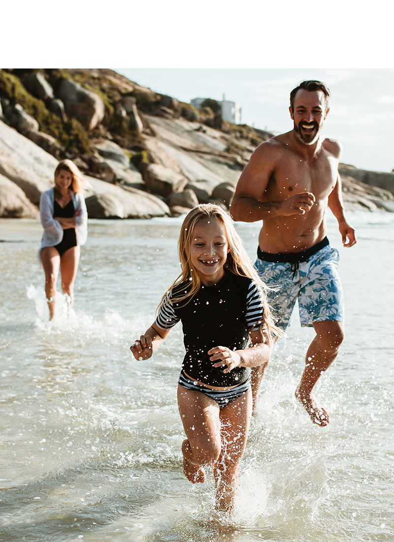 A family running in the water near a beach's shore