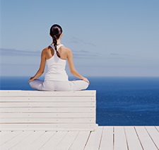 A woman meditating in front of a body of water