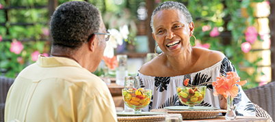 A smiling, older Black couple enjoying a meal