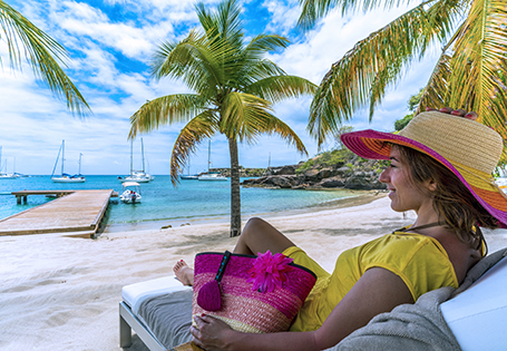 A woman in a sun hat sitting on a beach chair overlooking the water