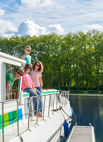 A smiling family standing on the deck of a houseboat